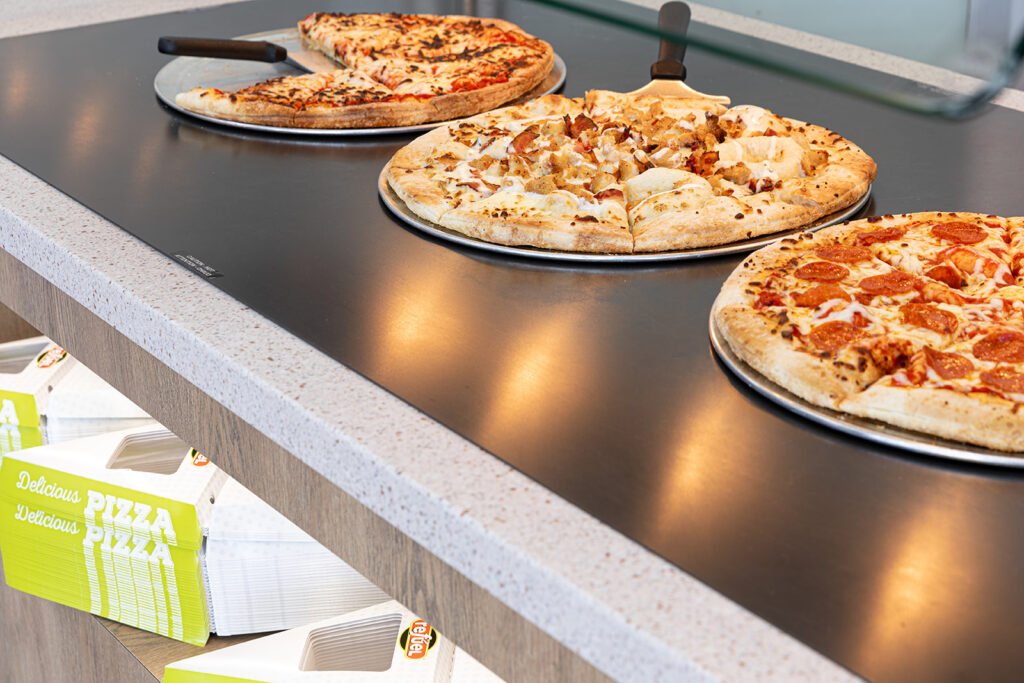Group of three pizzas on a countertop.